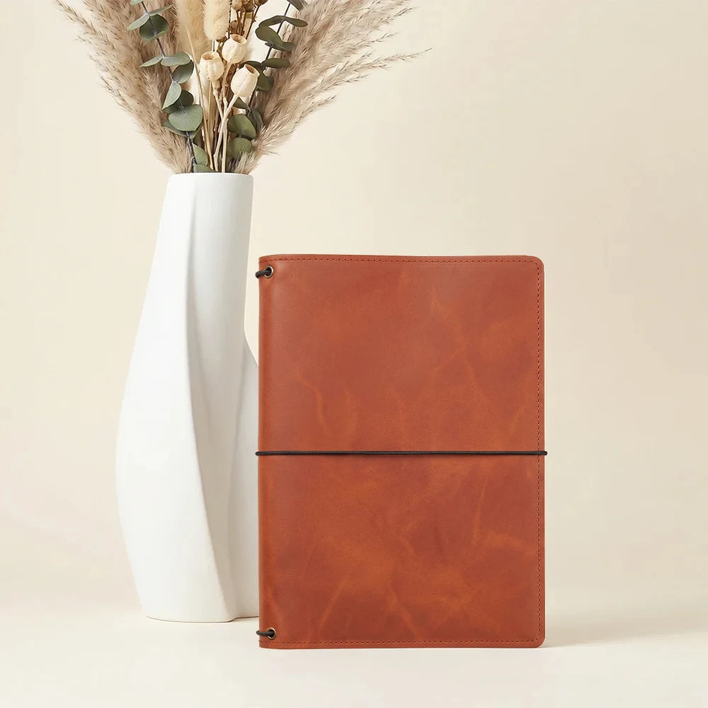 Handmade leather notebook wallet with refillable journal elastics and storage compartments.