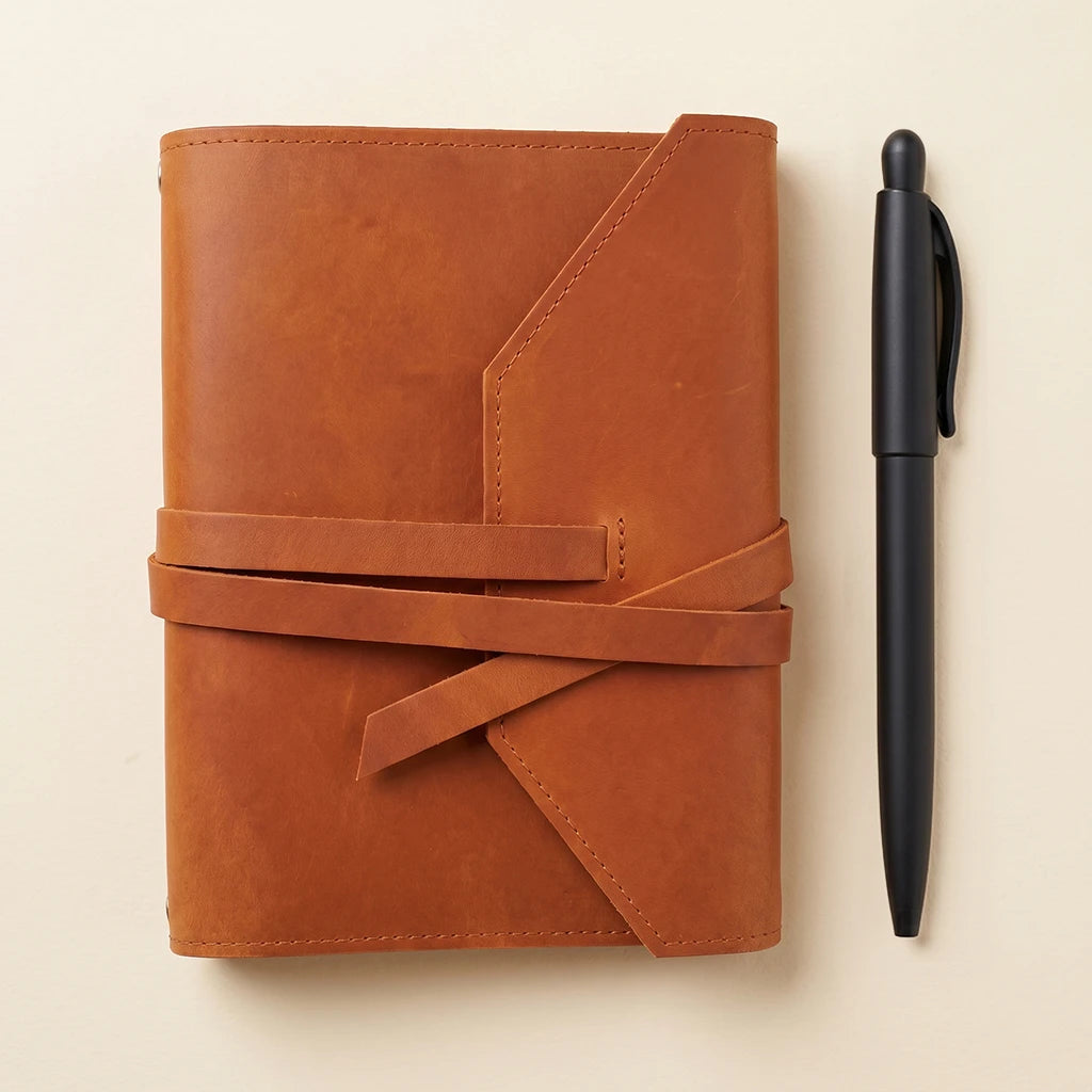 Refillable leather notebook cover featuring elastic closure and pen holder loop.