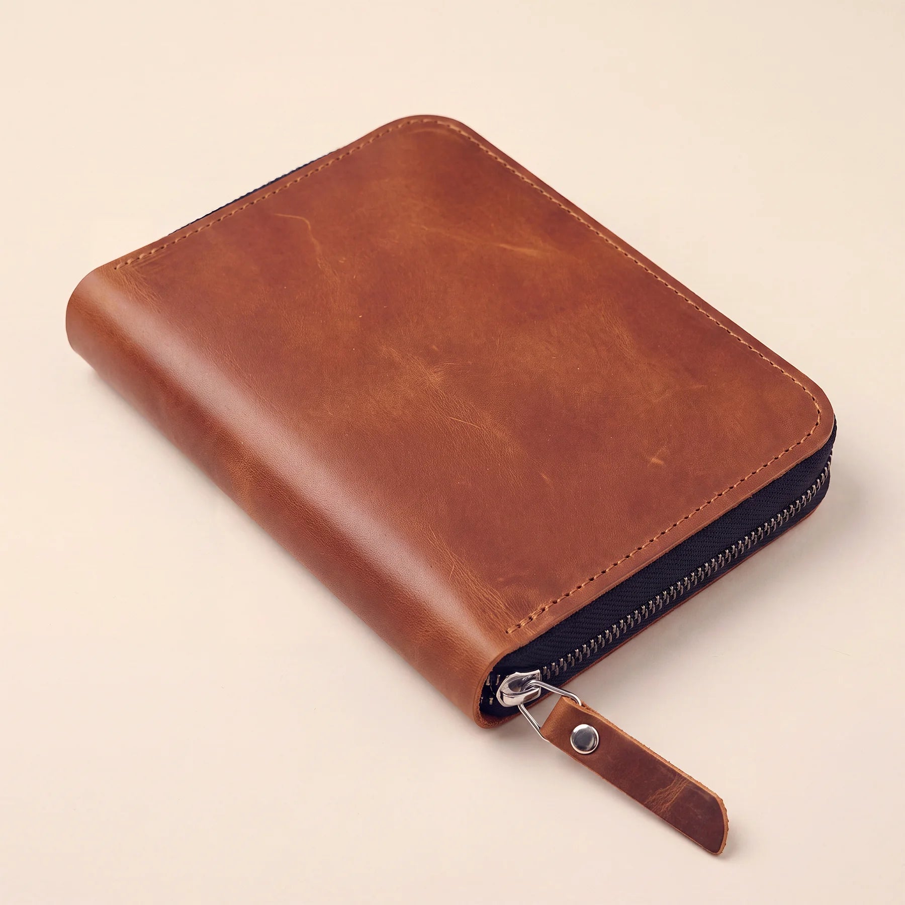 Handcrafted leather stationery case designed to protect pens with secure zip fastening.
