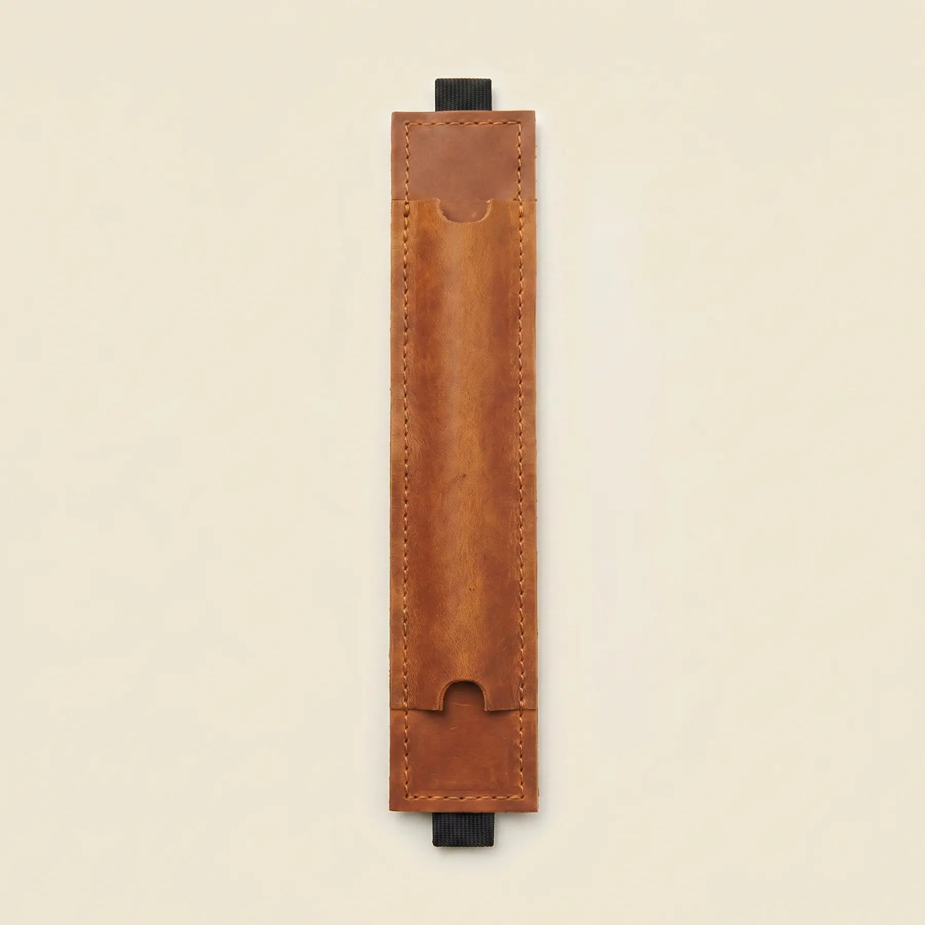 Brown leather notebook pen holder with elastic strap for everyday writing essentials.