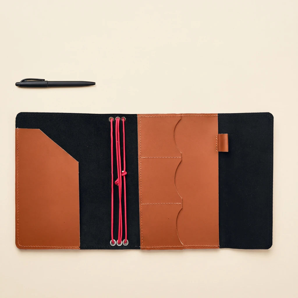 Handmade leather notebook enclosure with elastic straps and compact organizer interior