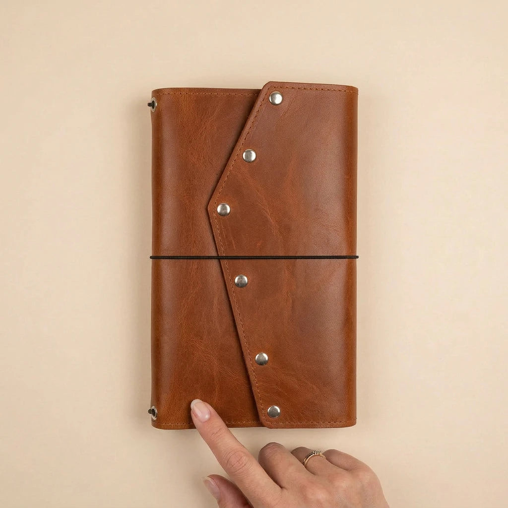 Brown leather notebook with metal rivets on a beige background