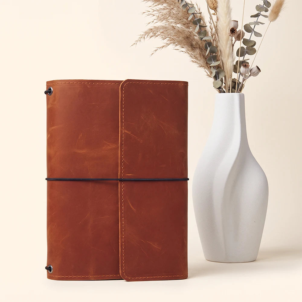Refillable journal cover crafted from genuine leather with functional storage and pen sleeve.