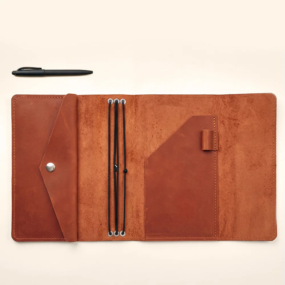 Handcrafted leather notebook organizer with refillable inserts and functional storage pockets inside.