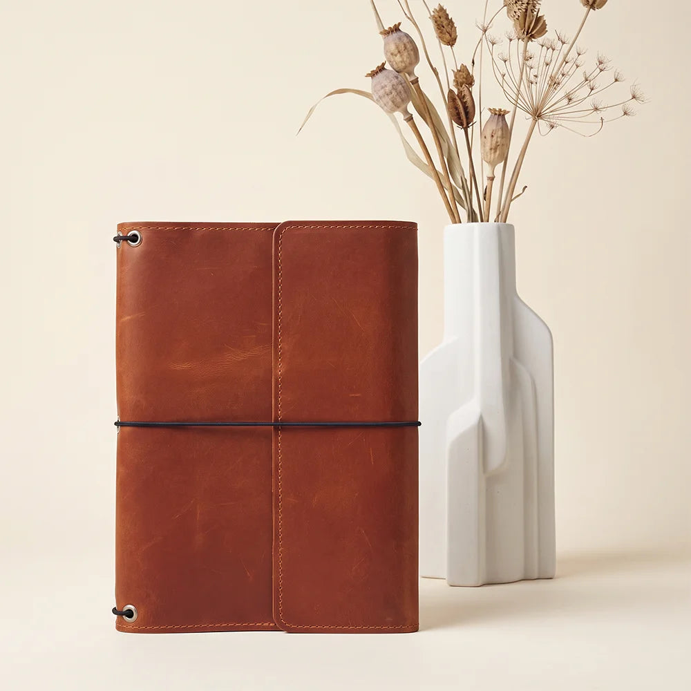 Handcrafted leather journal sleeve featuring elastic notebook holders for flexible daily organization.