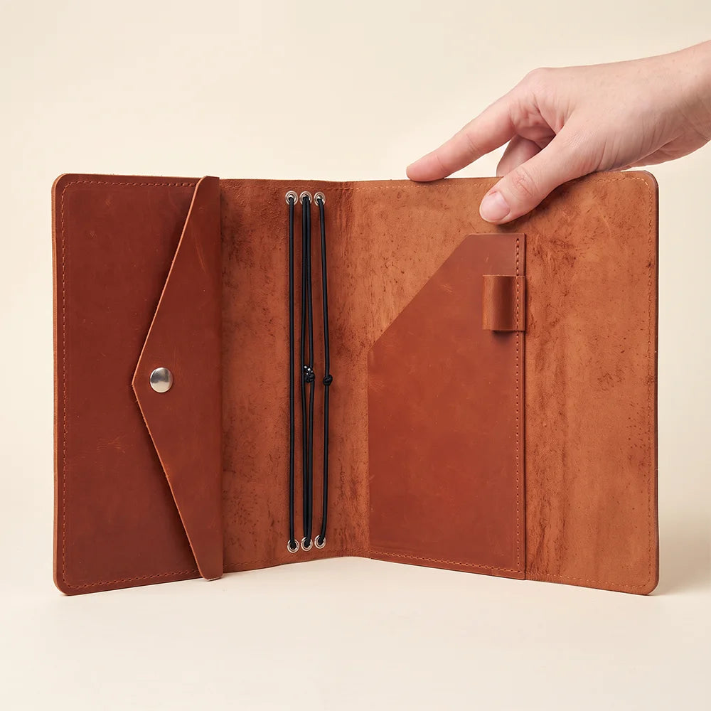 Premium leather notebook organizer featuring secure elastic inserts and built-in storage compartments.