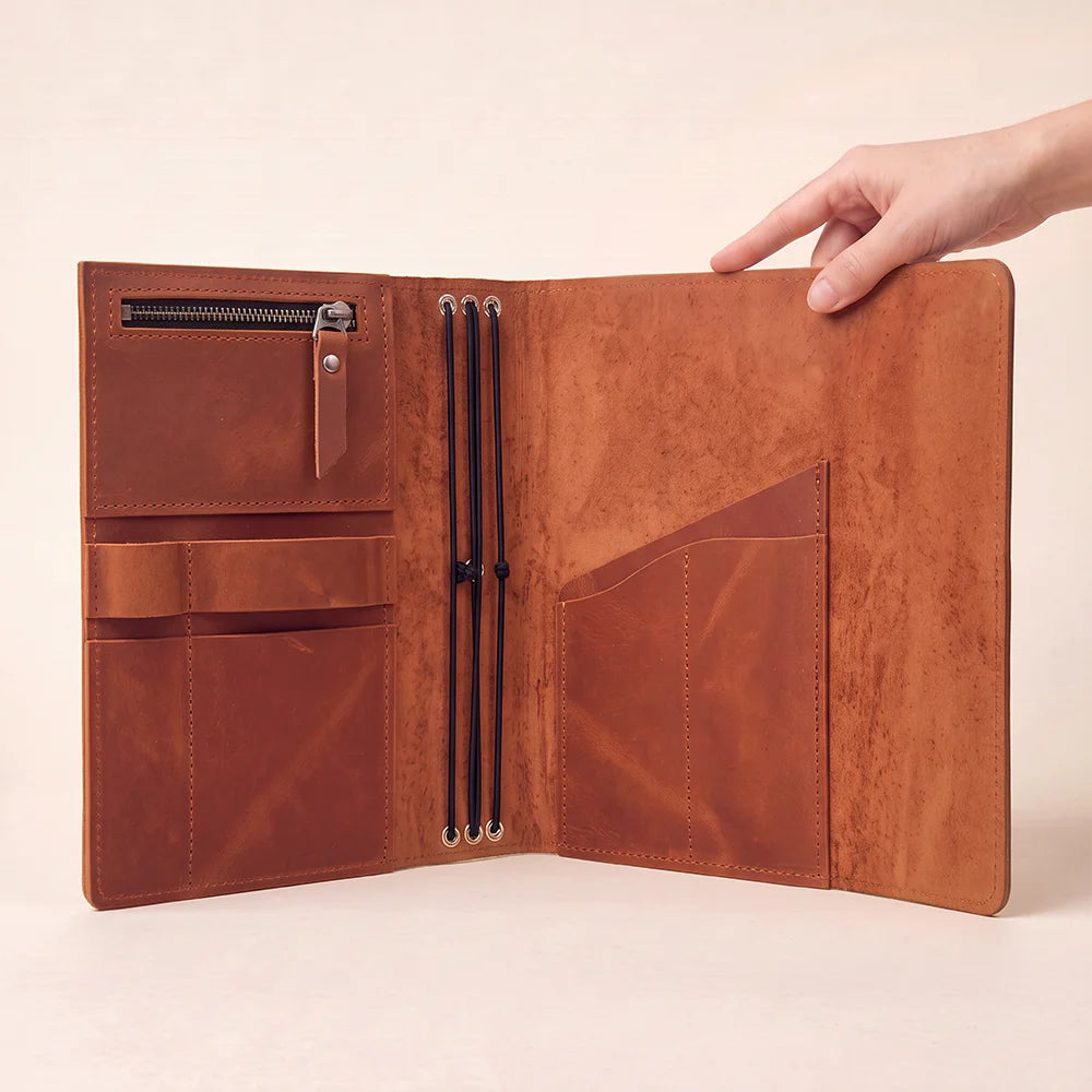 Leather planner sleeve crafted with practical inner pockets and an easily accessible pen loop.