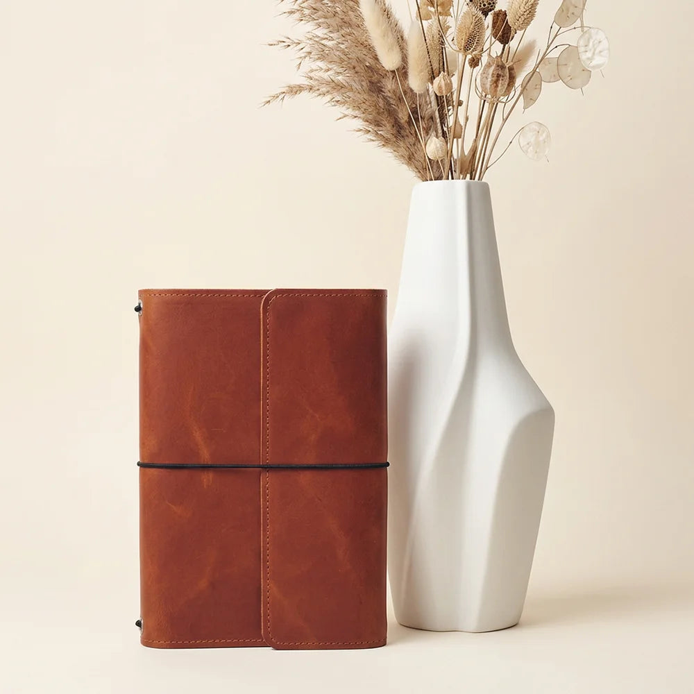 Artisan leather cover displaying structured interior pockets alongside a built-in pen retention loop.