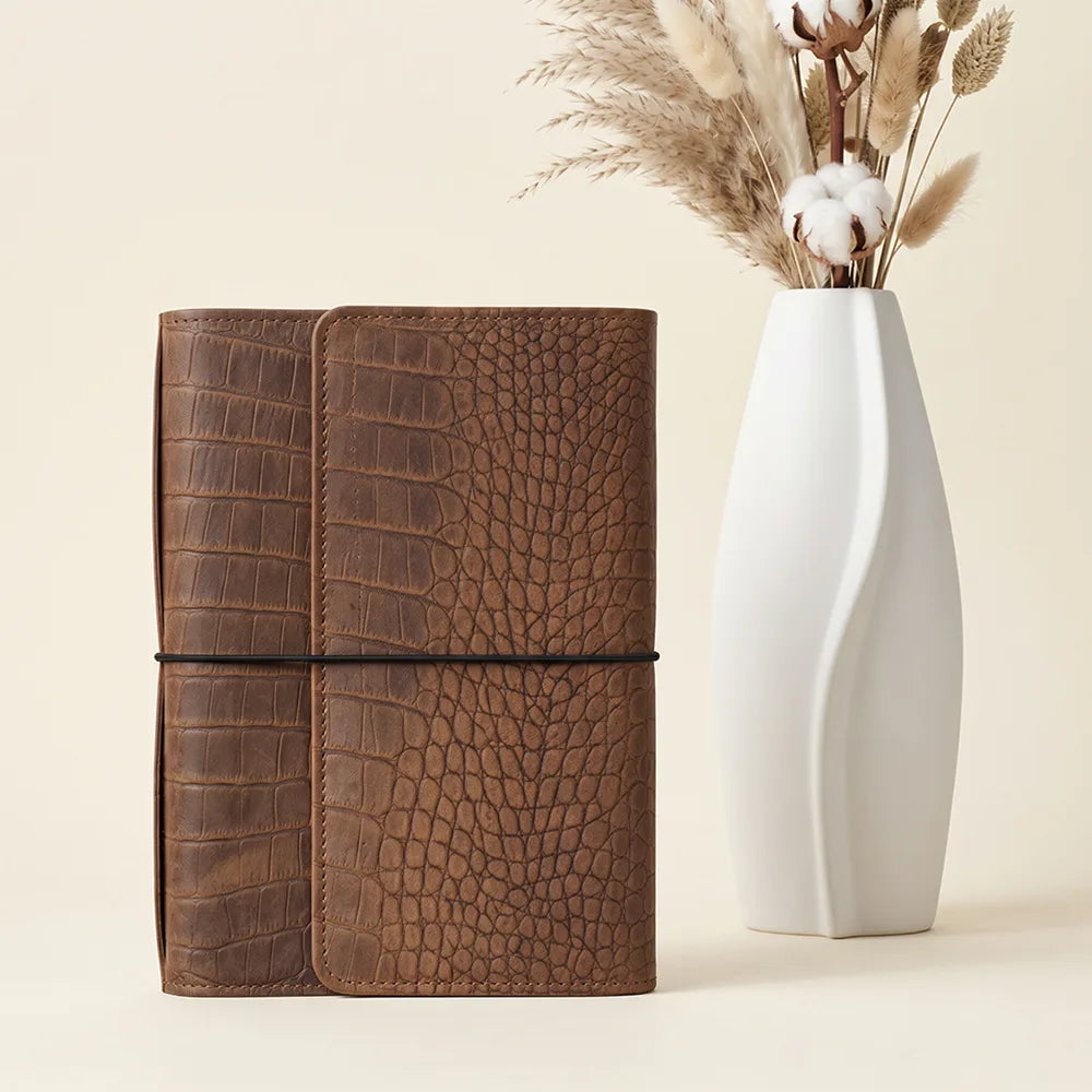 Open leather notebook cover featuring small pockets, a large zipper compartment, and pen loop.