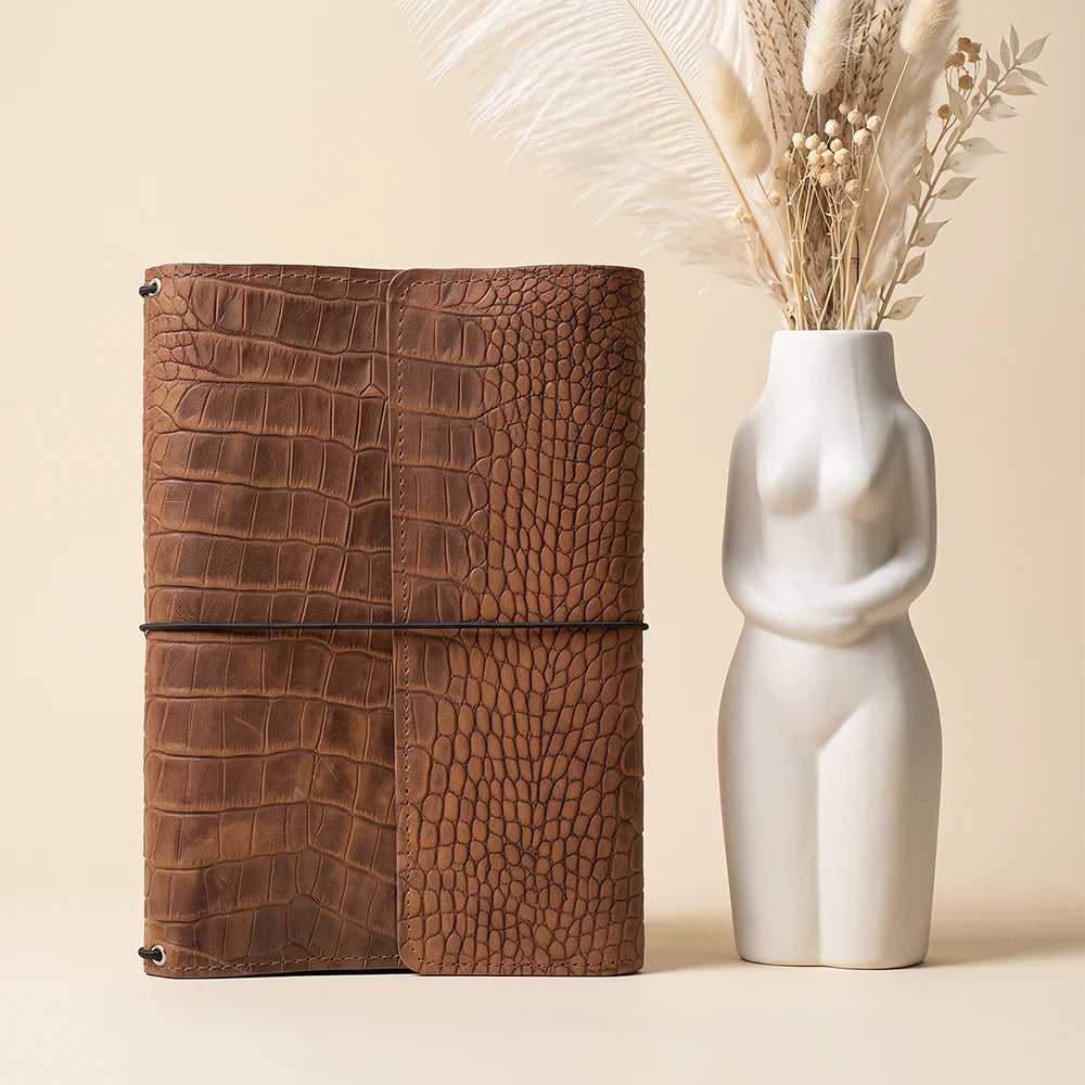 Brown leather notebook cover with refillable design and organized interior storage compartments.