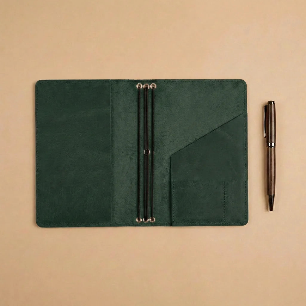 Green leather wallet with pen holder and a pen on a beige background