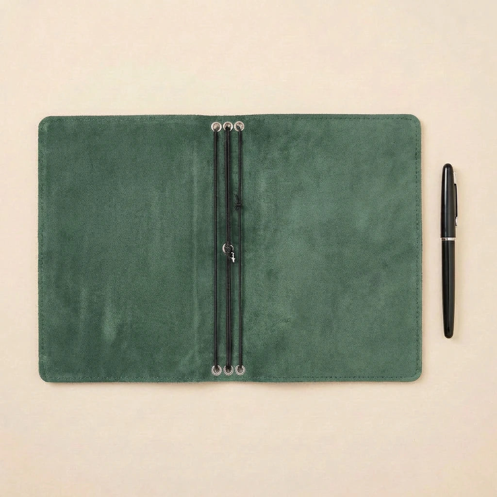 Green leather notebook with pen holder and a pen on a beige background