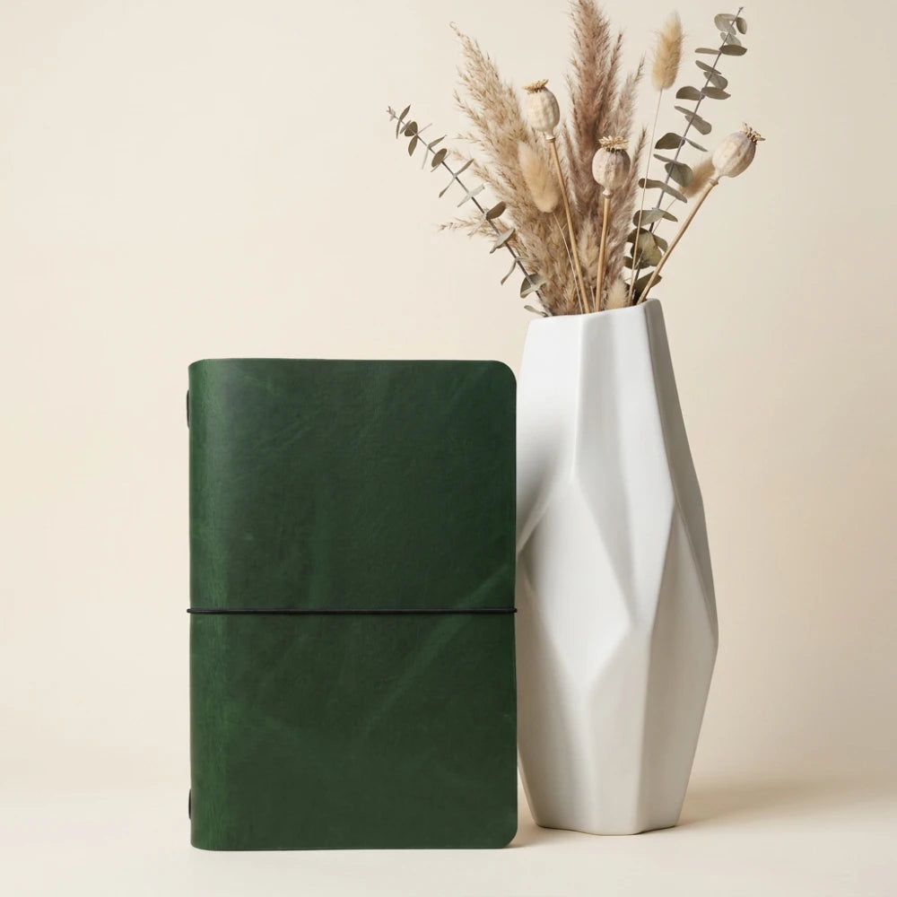Hand-finished leather notebook sleeve with clean structure and flexible elastic attachment.