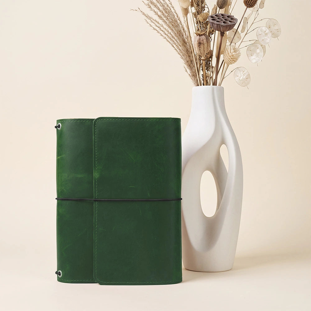 Handmade leather planner holder featuring organized storage pockets and dedicated pen sleeve.