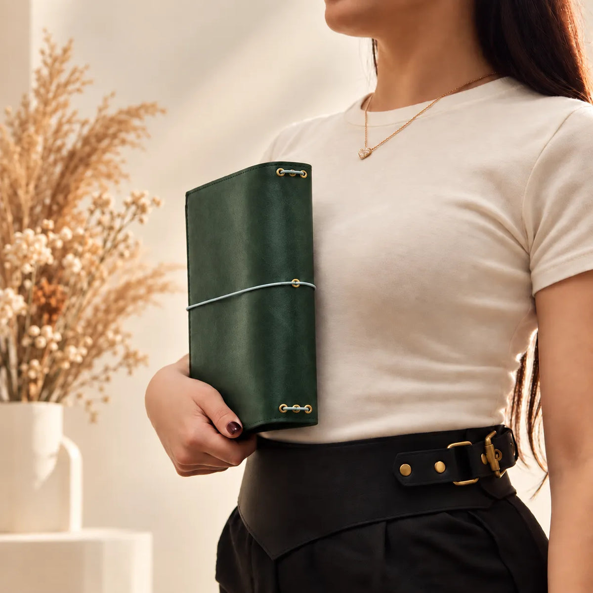 Young woman presenting a genuine leather journal cover while holding it naturally in both hands.