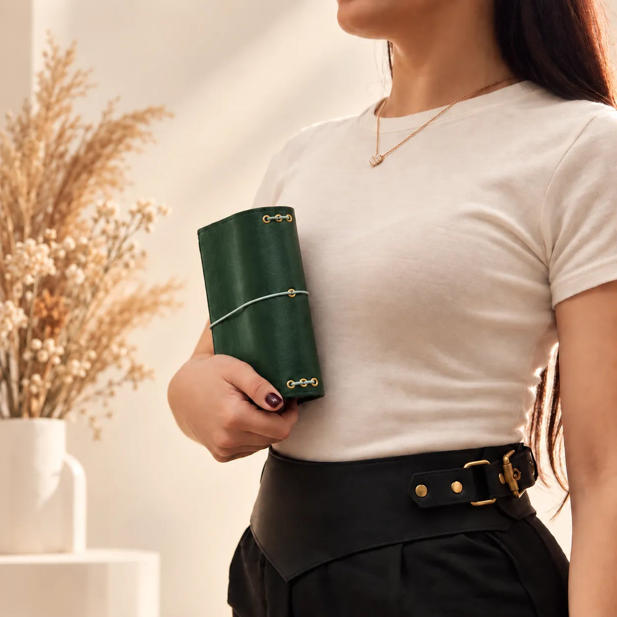 Female model displaying a natural leather journal cover with visible stitching and textured surface.