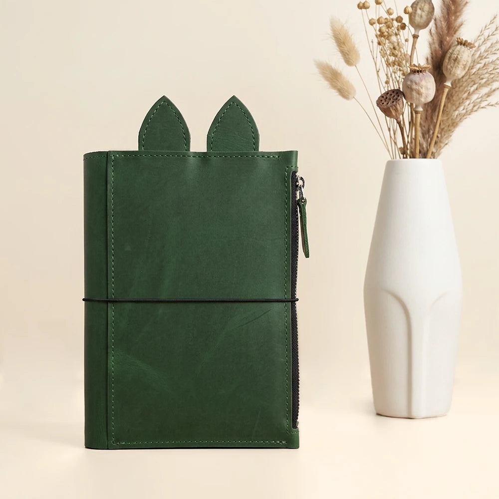 Handmade leather notebook organizer with large zippered pocket, pen loop, decorative ears, and elastics.