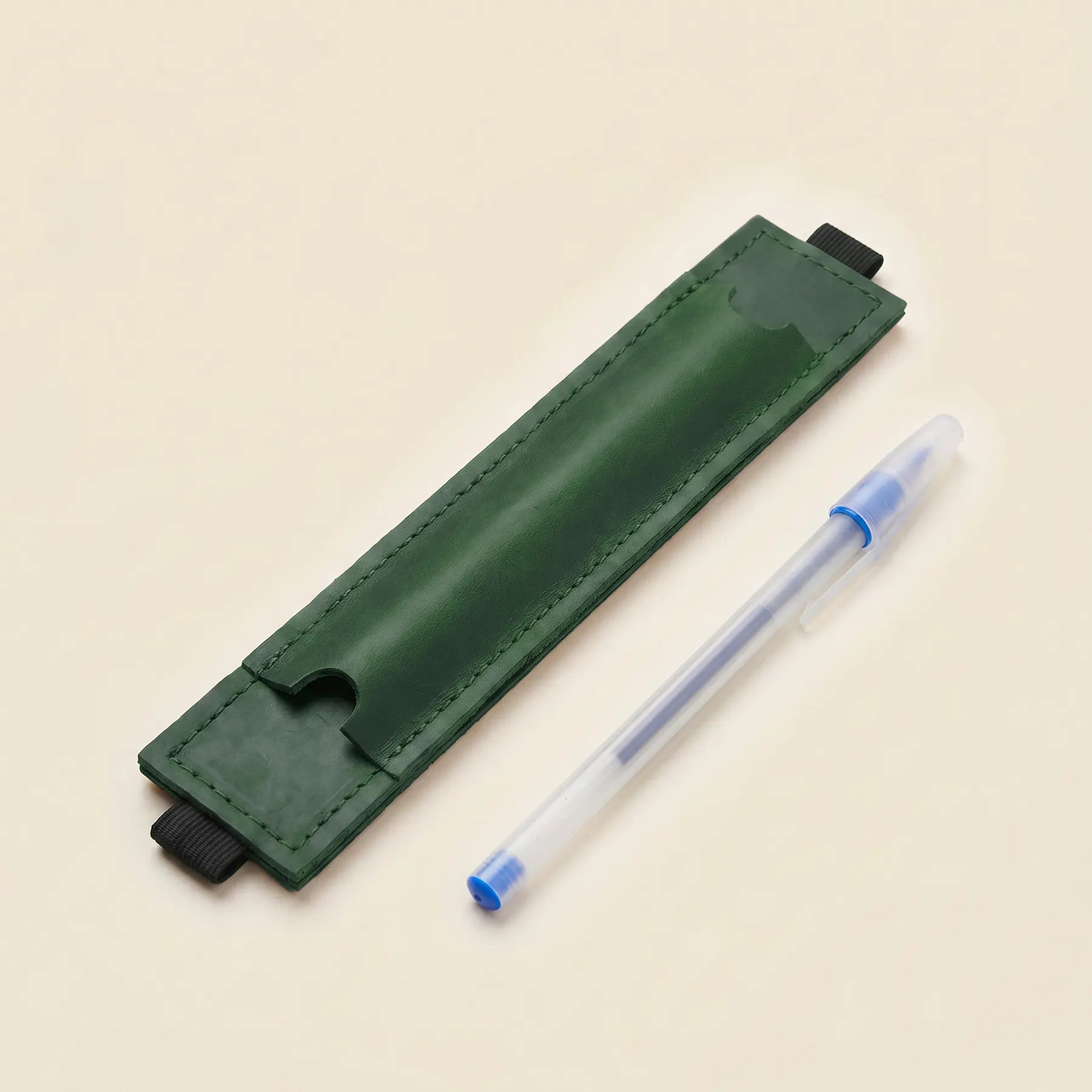 Reusable leather pen holder sleeve for notebooks with flexible elastic attachment band.