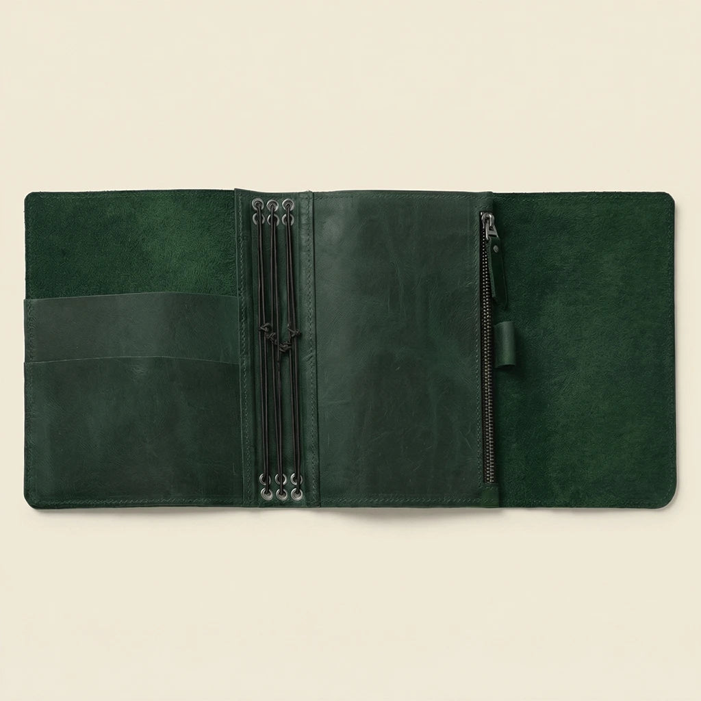 Green leather journal with zippers on a beige background