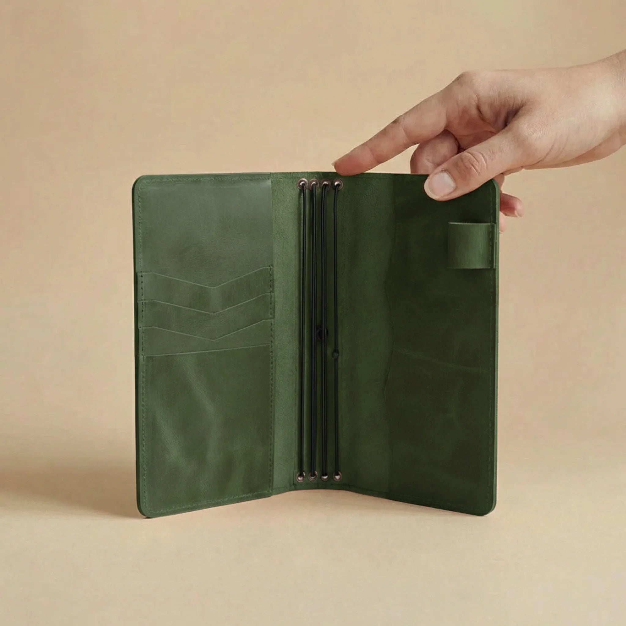 Green leather journal cover held open by a hand on a beige background