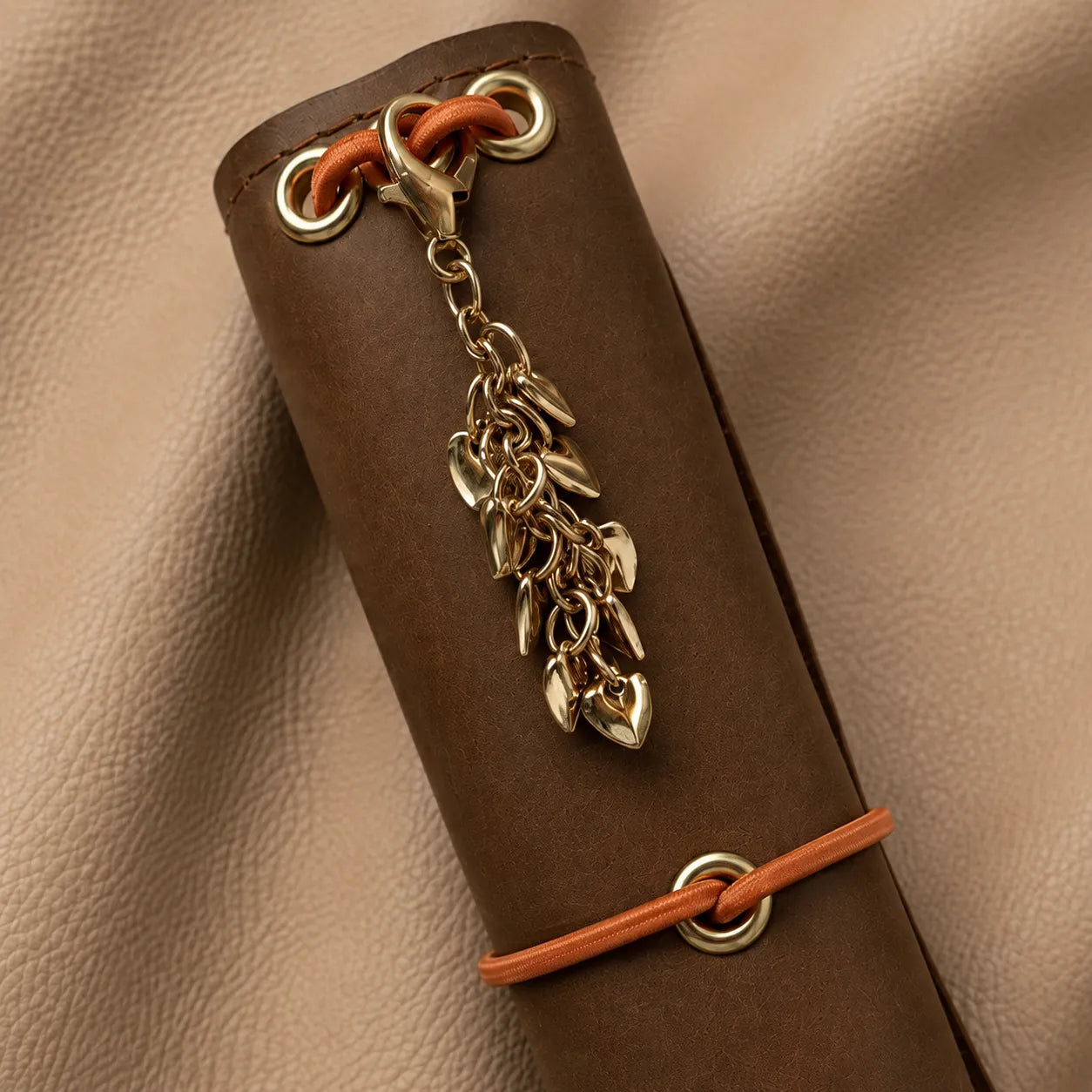 Heart-shaped journal charm attached to elastic bands, adding a stylish accent to leather notebook.