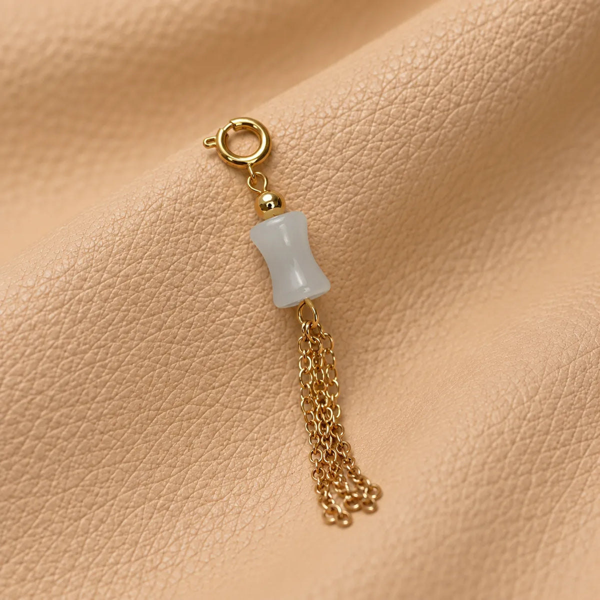 Decorative journal charm with a delicate bead attached to a leather notebook.
