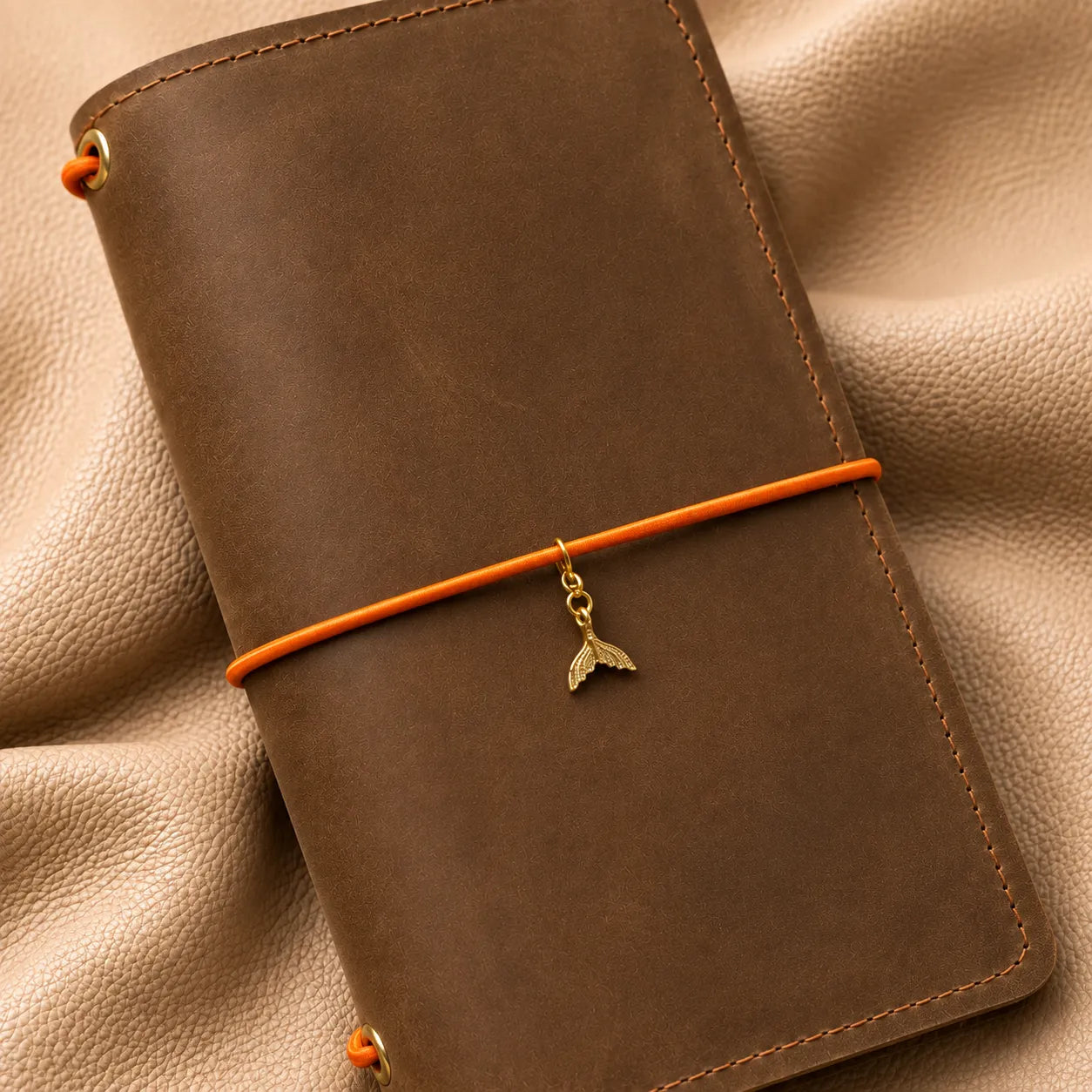 Whale tail journal charm attached to an elastic notebook band, elegant handcrafted planner accessory.
