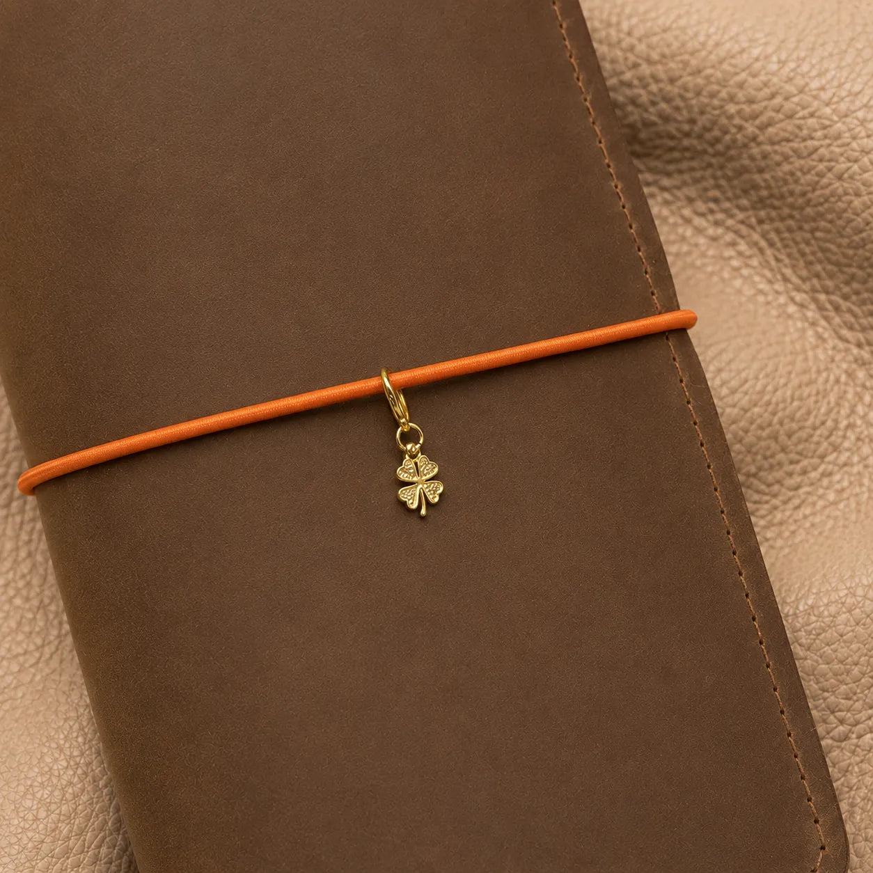 Clover-shaped notebook charm on elastic closure, stylish journal embellishment with metal attachment.