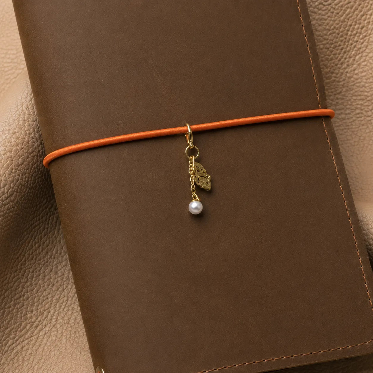 Leaf journal charm attached to notebook elastic band with elegant dangling metal leaves.