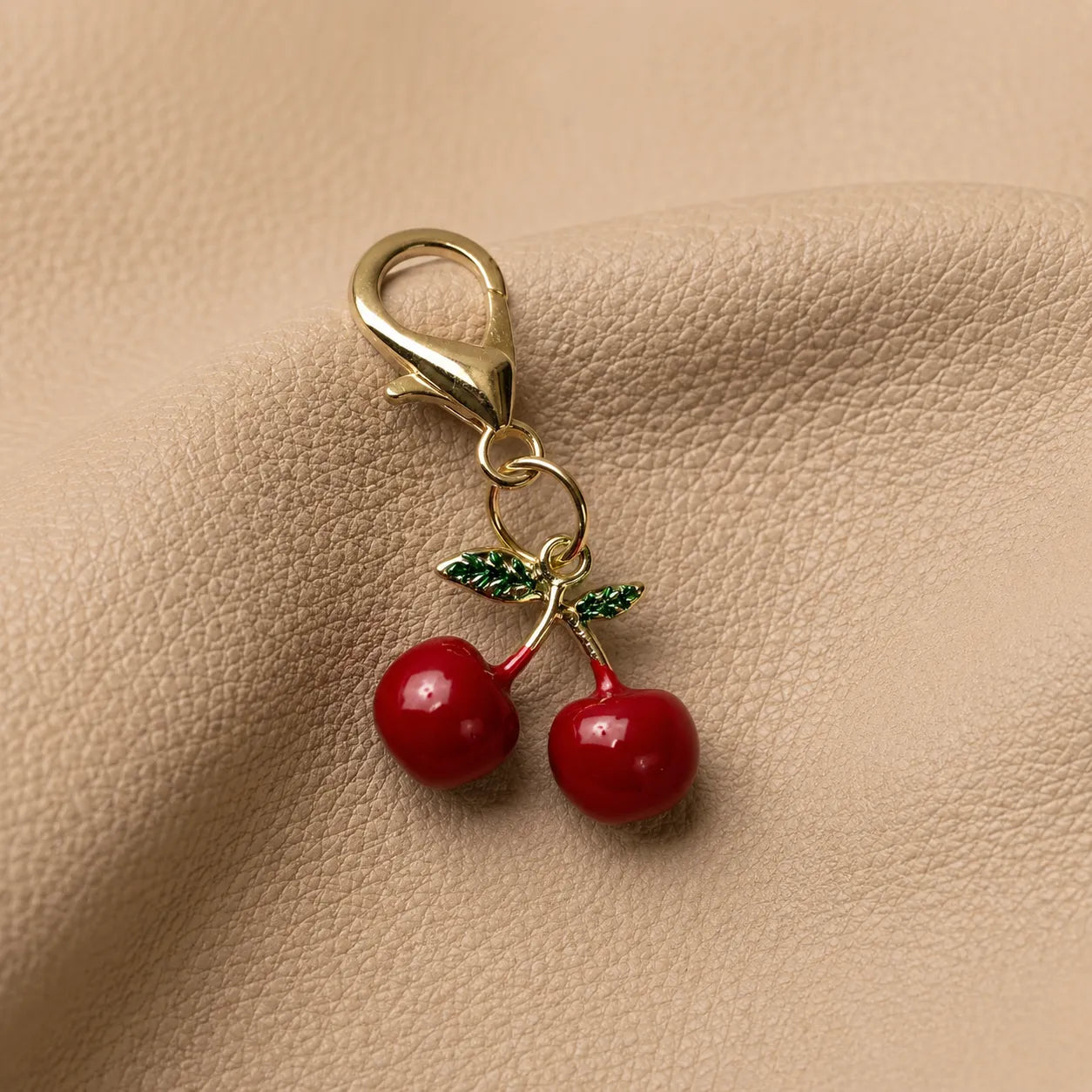 Cherry journal charm with metal attachment clipped onto elastic band inside a leather notebook cover.
