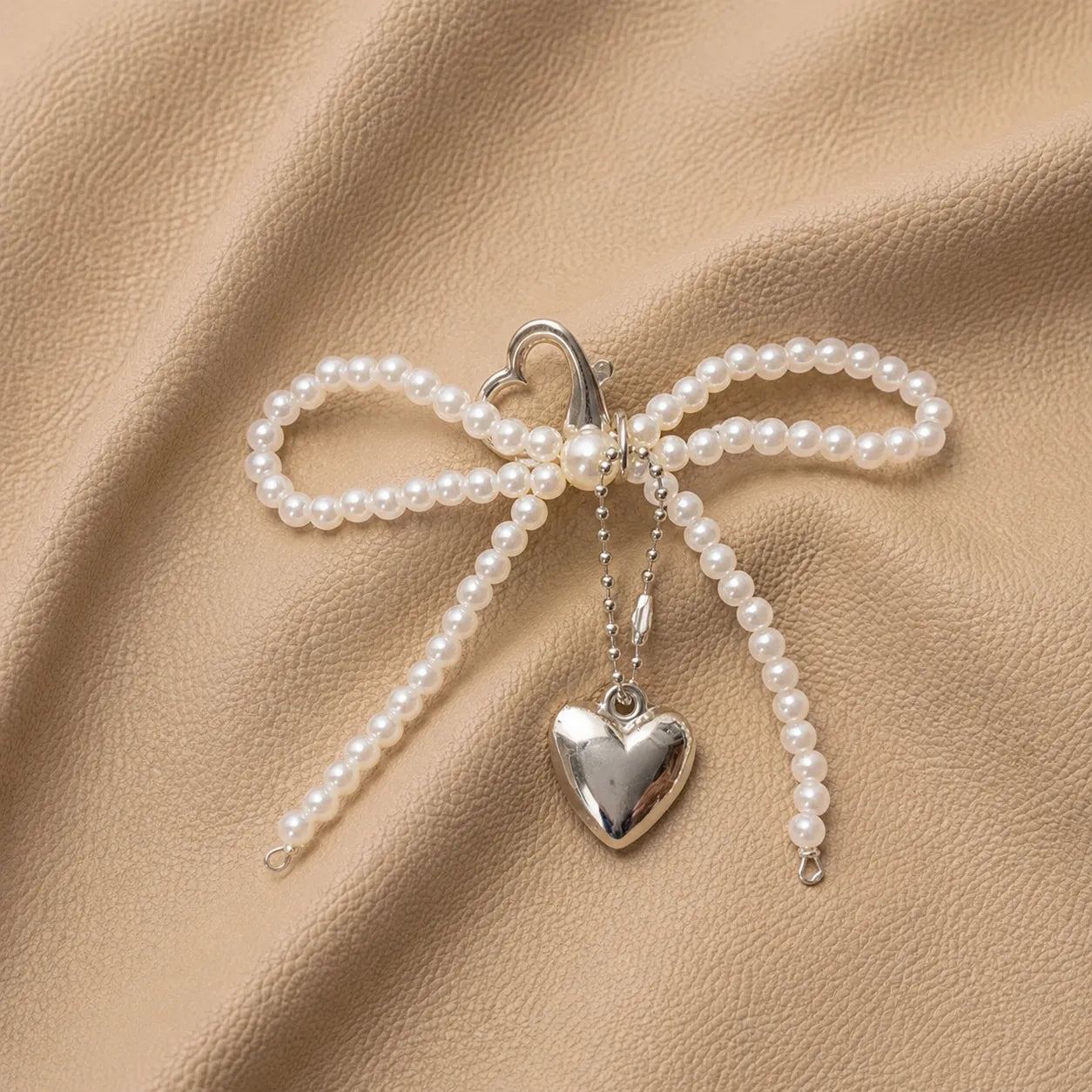 Decorative journal charm with beaded bow and metal clip attachment.