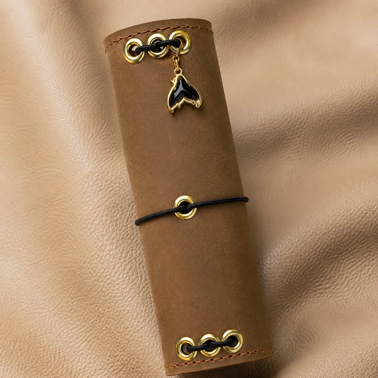Whale tail journal charm attached to a leather notebook, decorative planner and journal accessory.