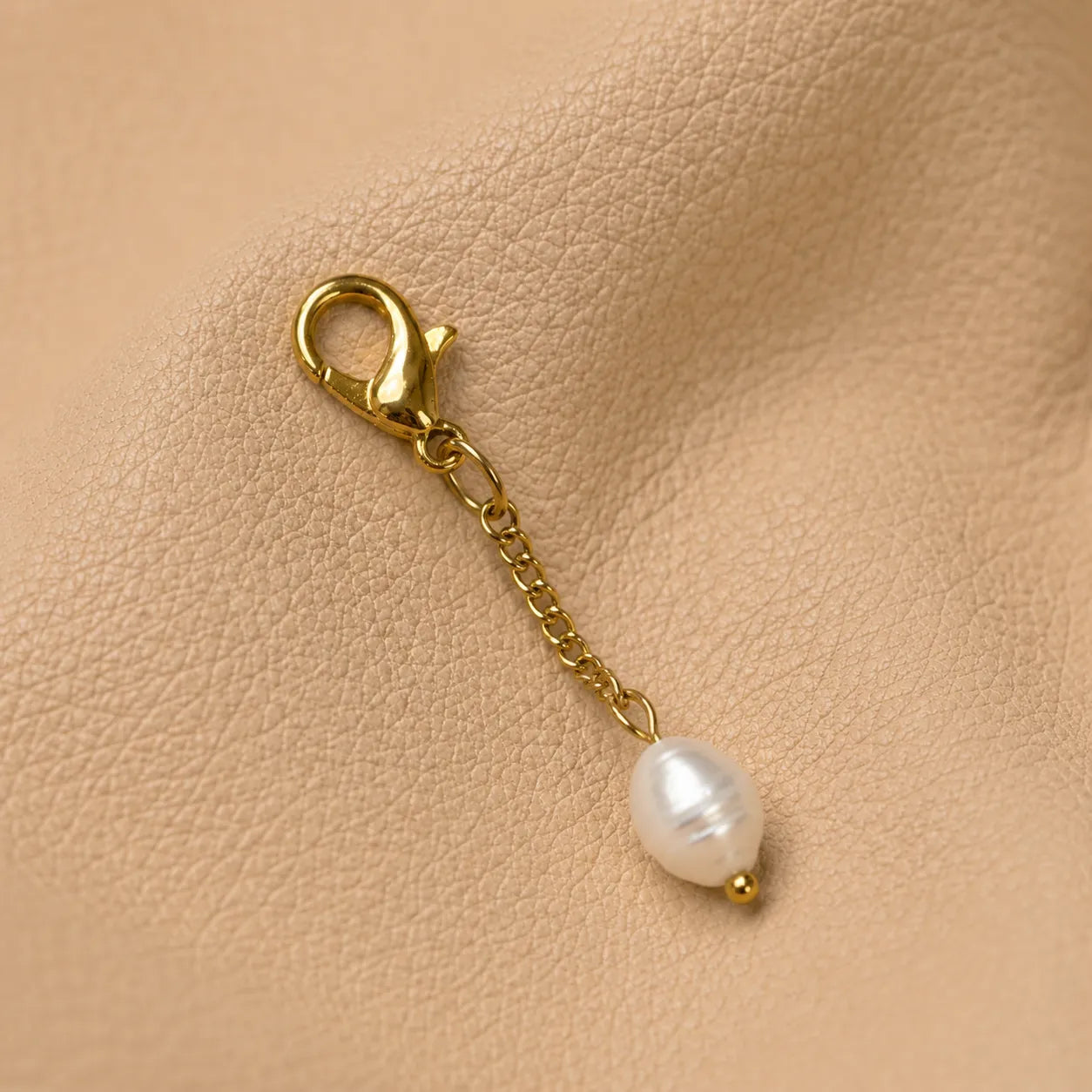 Beaded notebook charm decorating elastic closure with elegant metal clip and handcrafted accent.