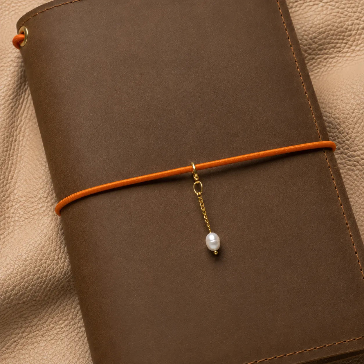 Journal charm with decorative bead attached to notebook elastic band accessory.