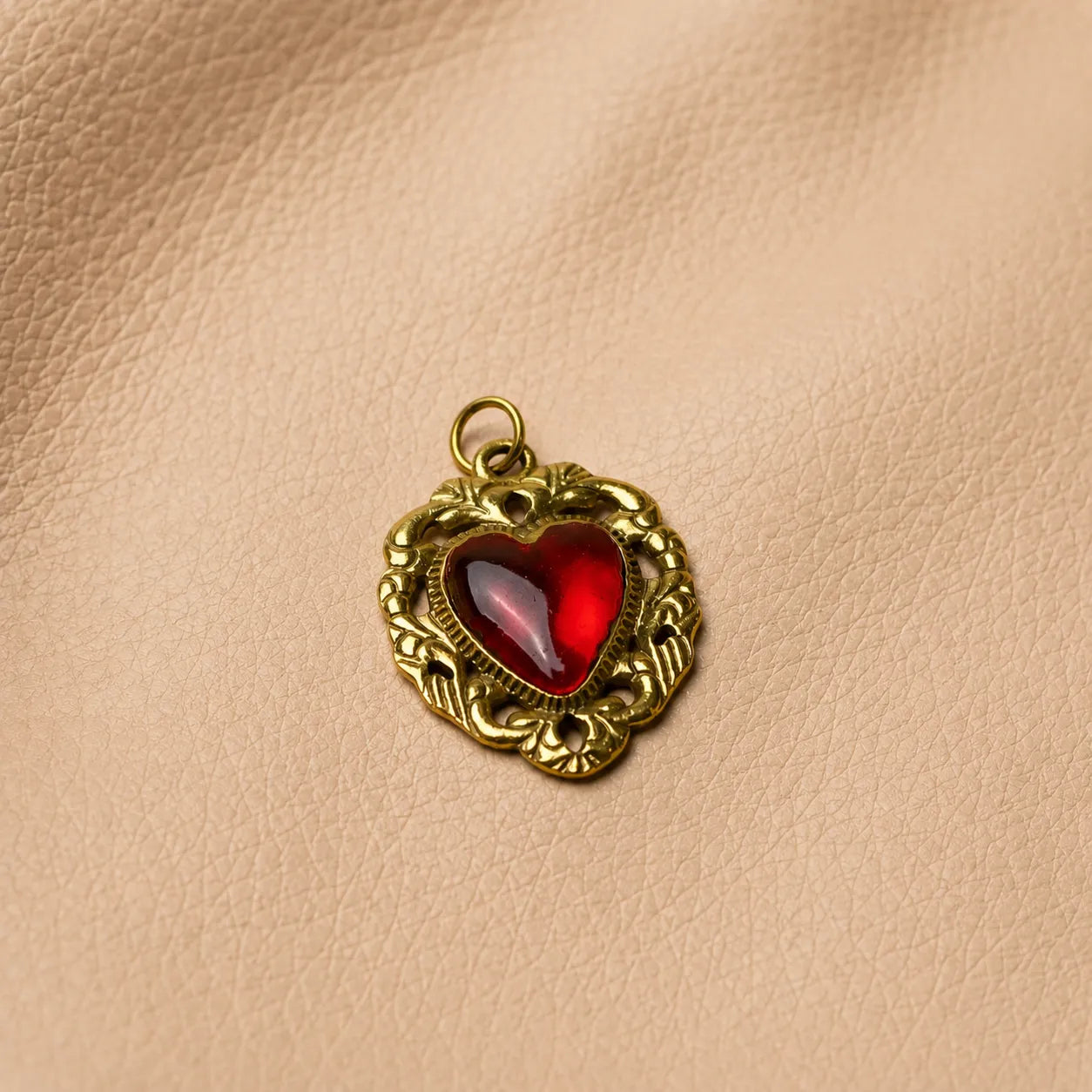 Heart-shaped journal charm attached to leather notebook elastic band, elegant decorative planner accessory.