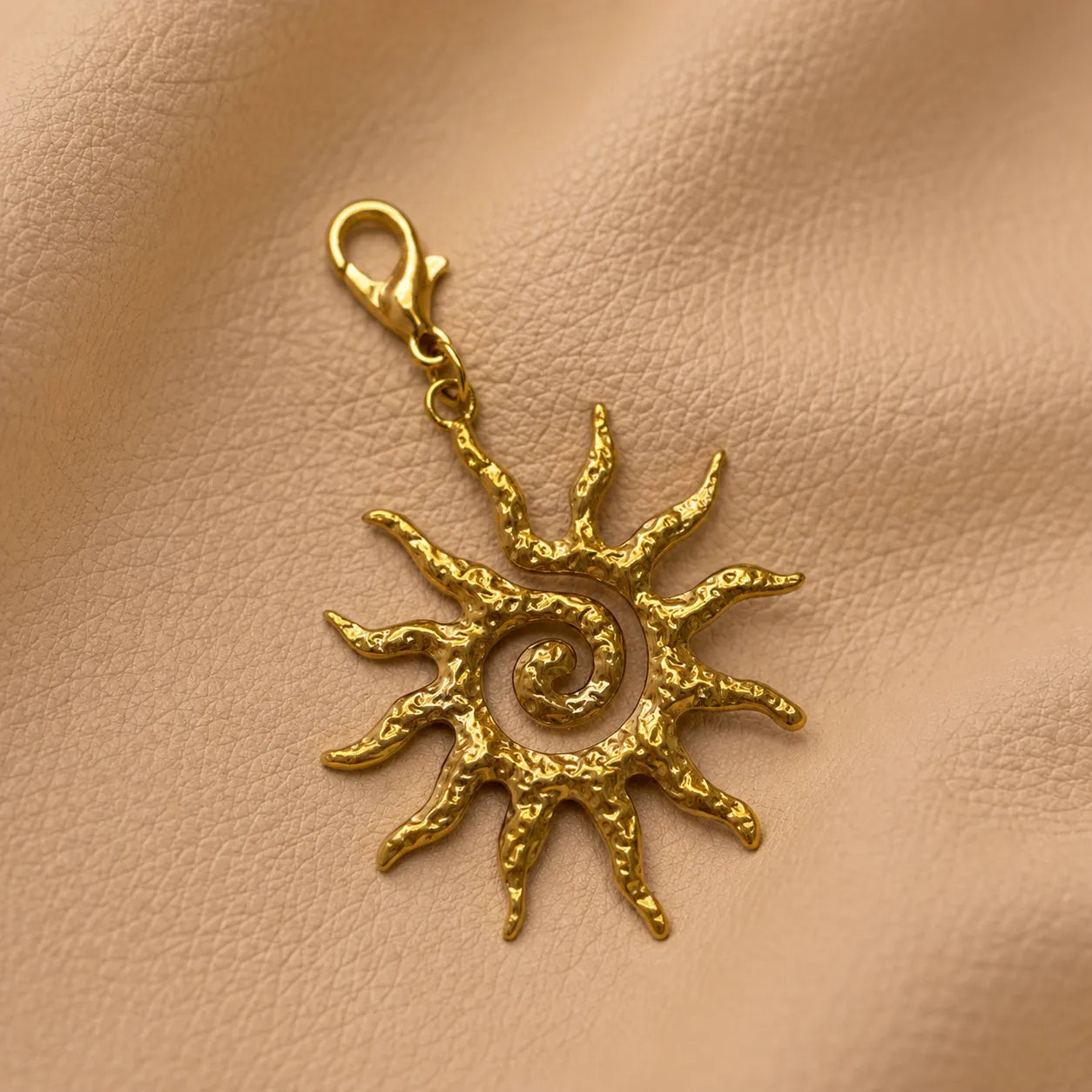 Decorative sun journal charm secured on notebook elastic, stylish accessory for refillable travel journals.