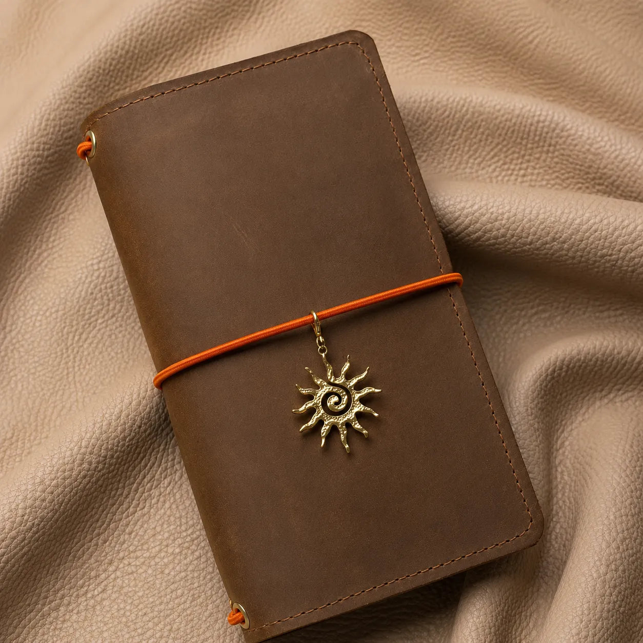 Sun-shaped journal charm attached to notebook elastic band, elegant metal accessory for planners and journals.