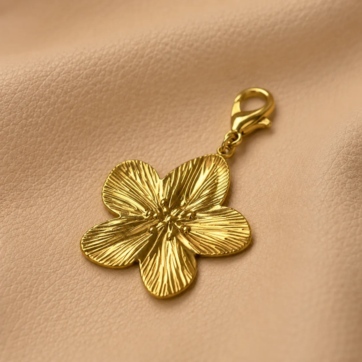 Metal flower notebook charm with decorative bead clipped onto refillable leather journal elastic band