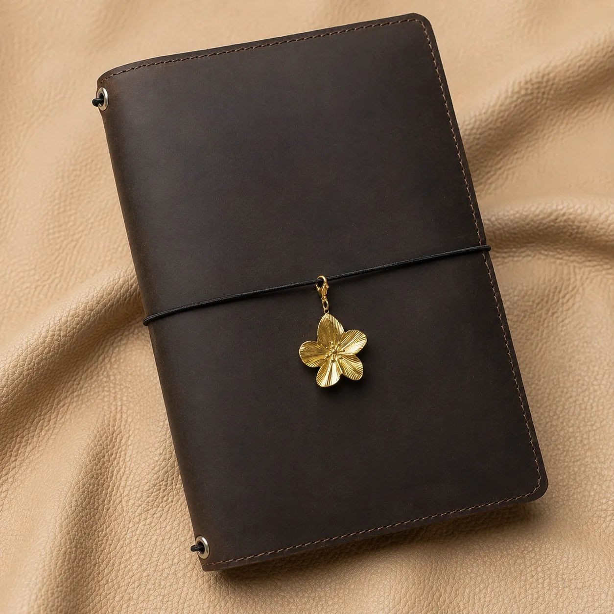 Flower journal charm attached to leather notebook elastic, elegant decorative planner accessory close-up