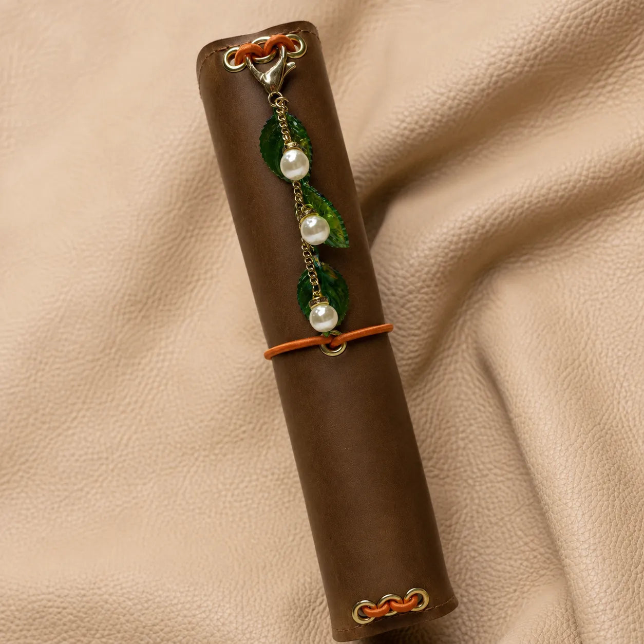 Decorative leaf journal charm accessory for travel notebooks with elastic band attachment.