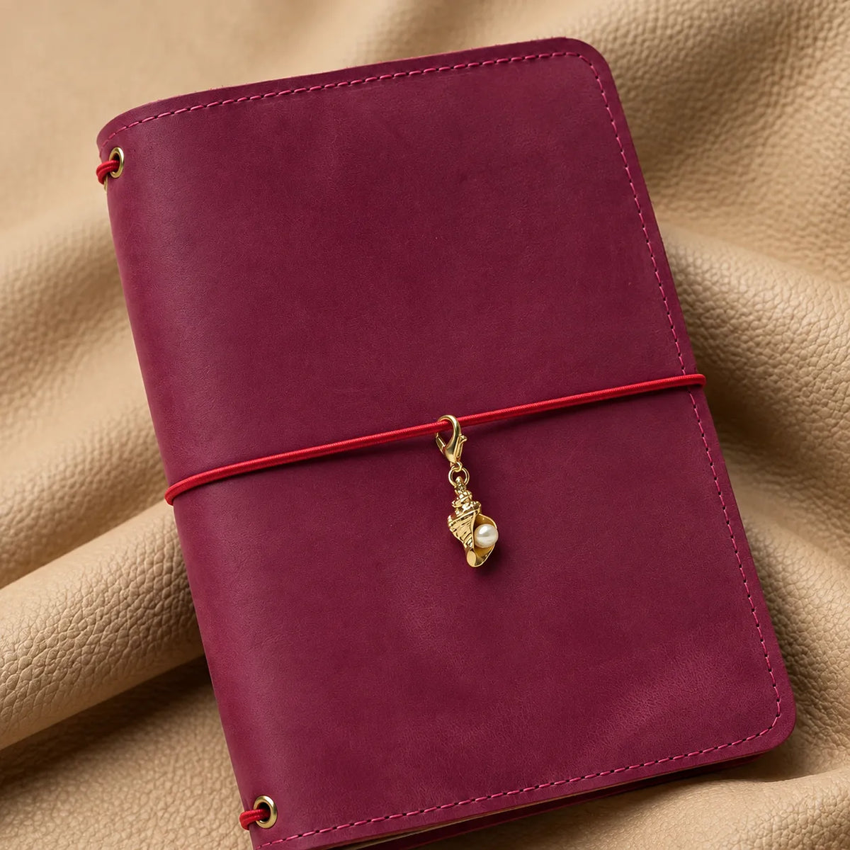 Small bead charm adorning a leather journal cover with an elegant hanging design.