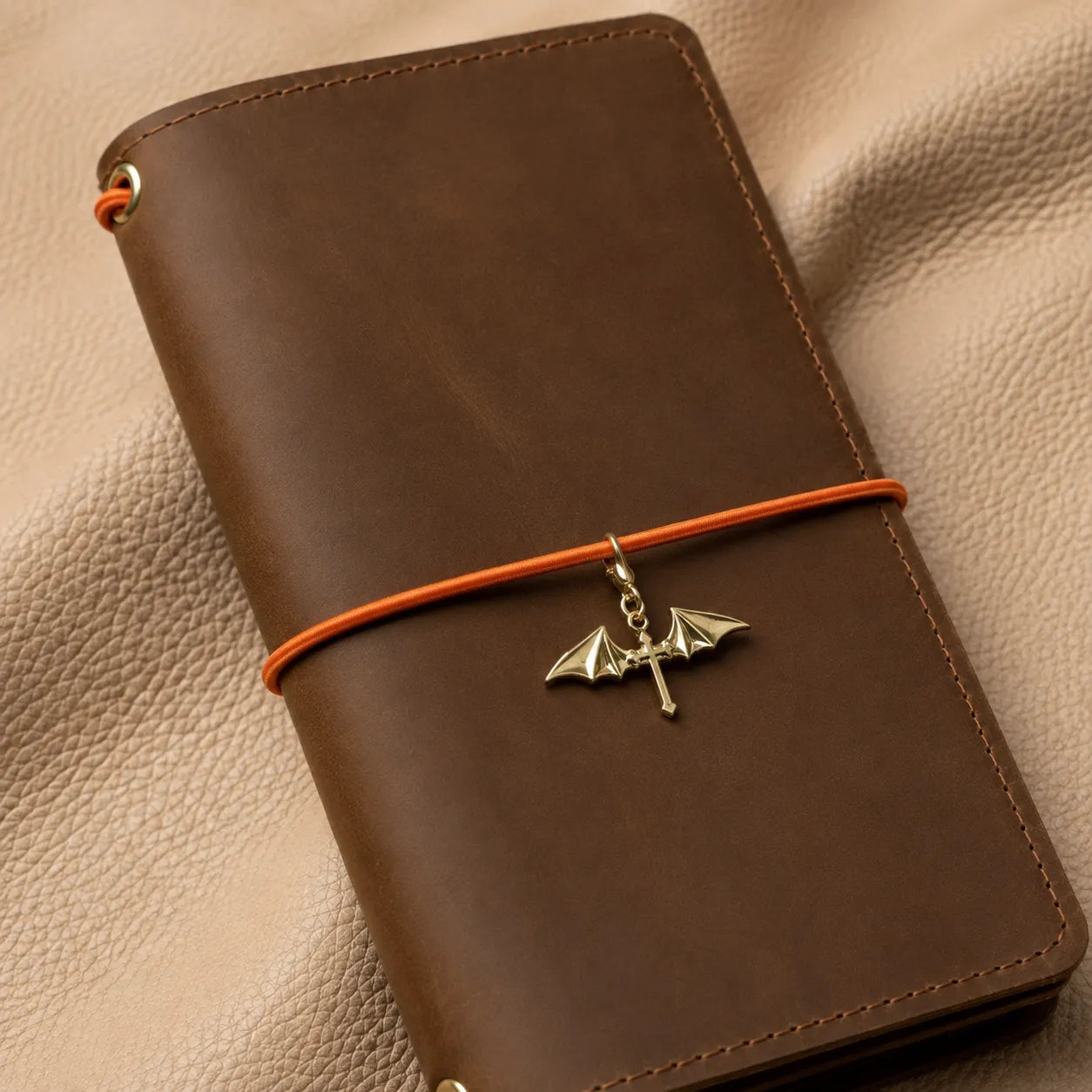 Decorative winged cross charm on notebook elastic, stylish journal accessory in silver finish