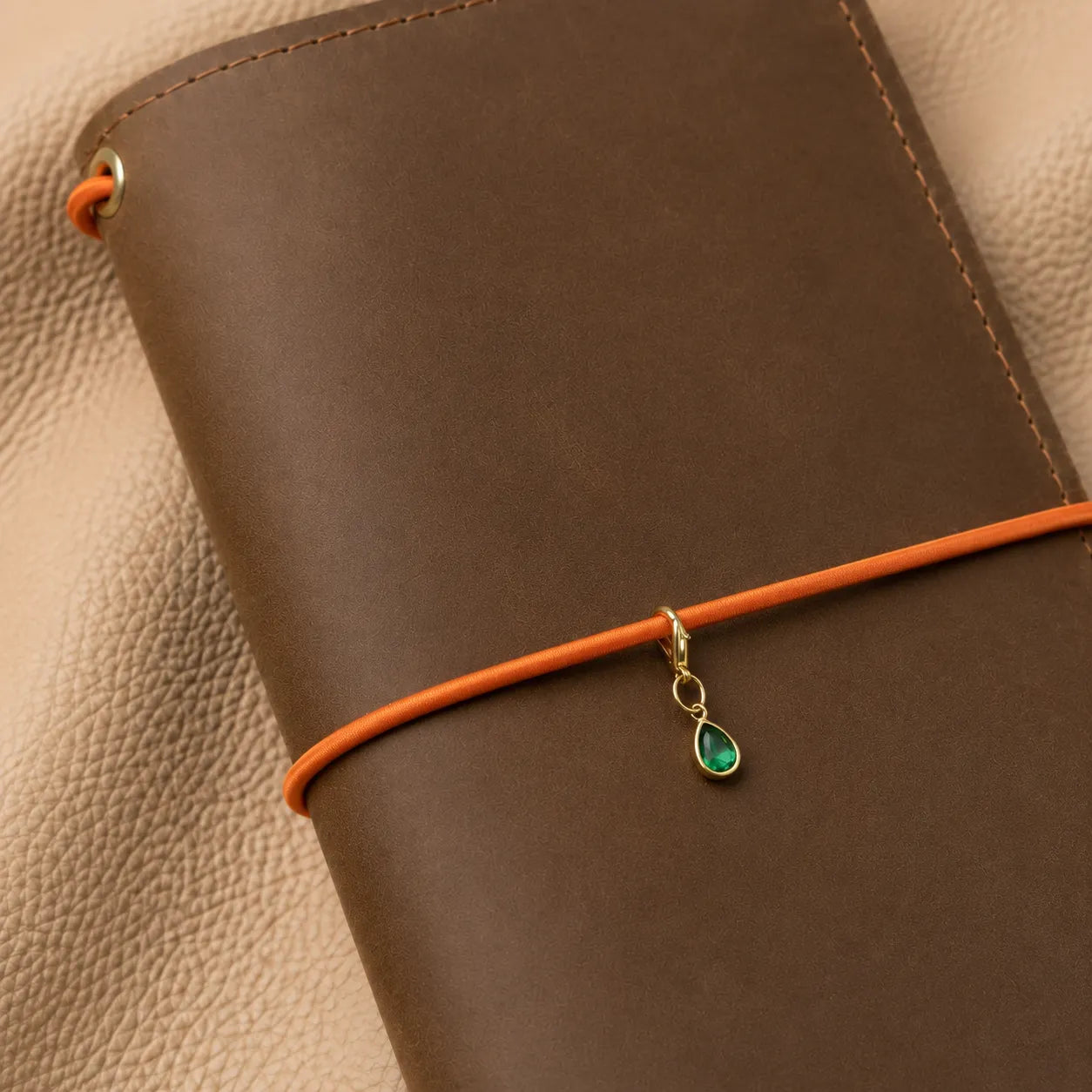 Close-up of beaded notebook charm hanging from elastic bands, stylish journal decoration accessory.