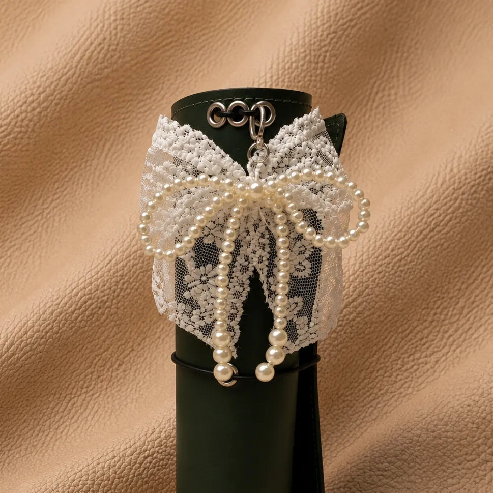 Decorative journal accessory featuring lace bow, pearl accents, and metal attachment.