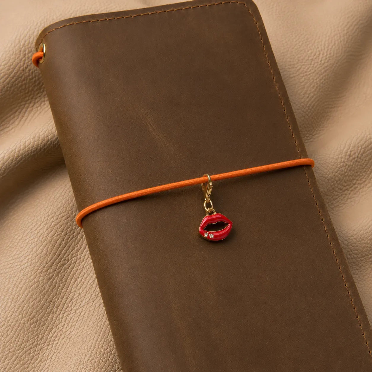 Lips-shaped journal charm attached to notebook elastic bands, stylish decorative accessory for travelers notebook.