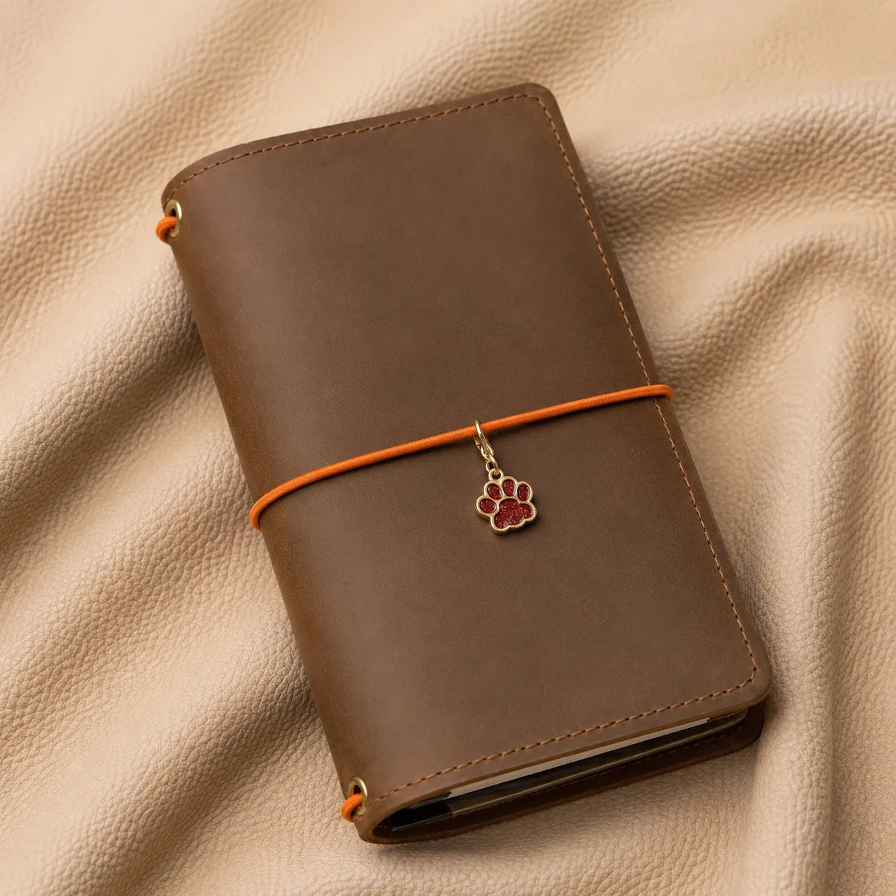 Cat paw journal charm attached to elastic bands, elegant notebook accessory with decorative metal clasp.