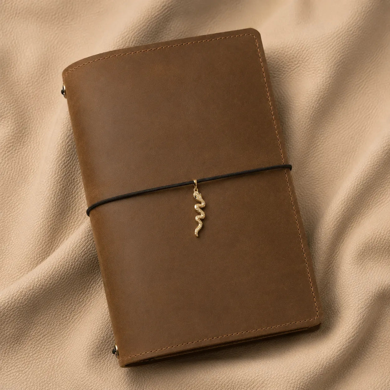 Decorative snake notebook charm hanging from elastic journal band for personalized leather planner