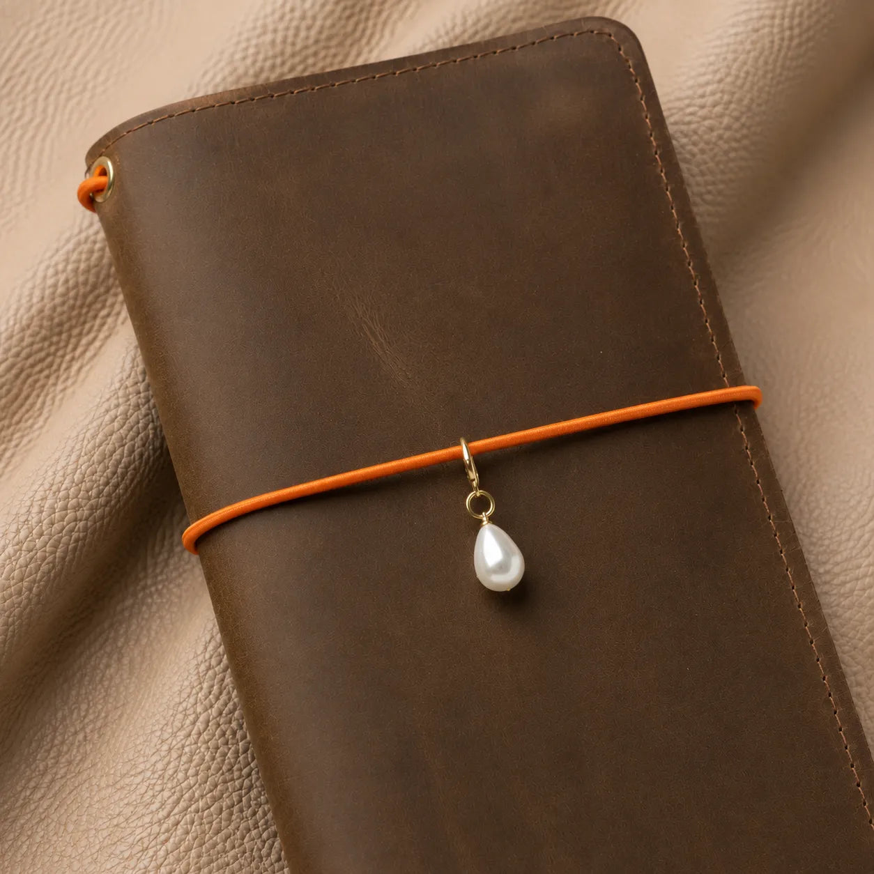 Metal journal charm attached to notebook elastic bands, elegant decorative accessory for travel journals.