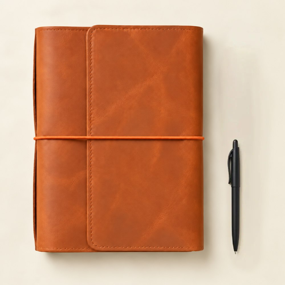 Orange leather journal cover with six elastic bands for holding multiple notebooks securely.