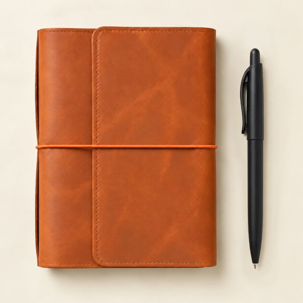 Orange handmade leather cover with six elastic bands and convenient pockets for personal essentials.